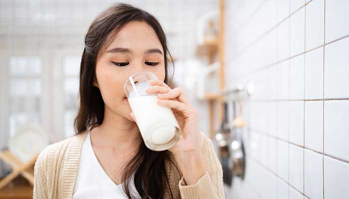 A young woman drinks a glass of milk