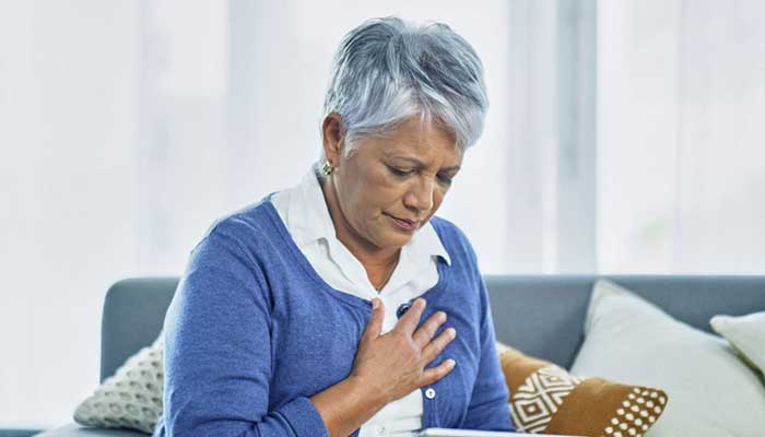 An older woman holds her chest