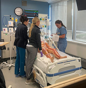 Group of medical professionals standing at a training bed.