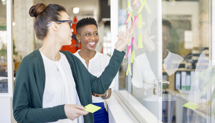 Two employees hanging notes on a wall