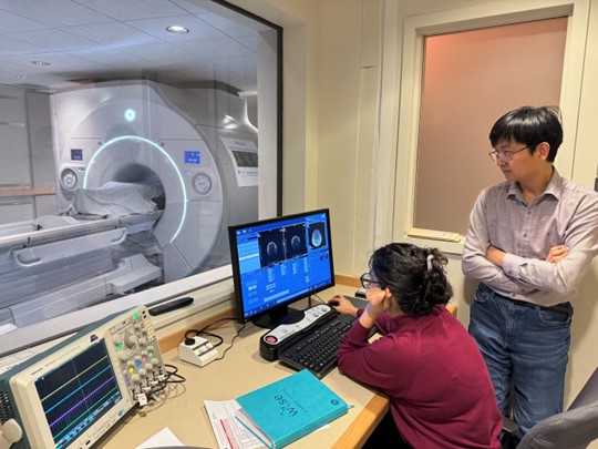 Researchers looking at a computer screen outside of the MAGNUS scanner