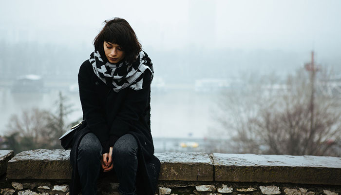 Young woman sitting outside looking down